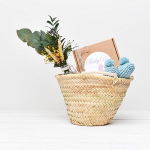 Una de nuestras cestas regalo que incluye dos masajes especiales Babybe, unos patucos de recién nacido y botecido de cristas con flores preservadas