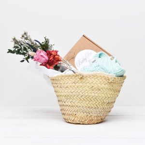 Cesta de regalo con conjunto aguamarina de primera puesta, flores preservadas color rosa y caja regalo con una noche de salus para los recién papás