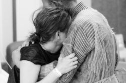 Pareja de futuros papás el día del parto. El papá sostiene a la mamá en una dura contracción